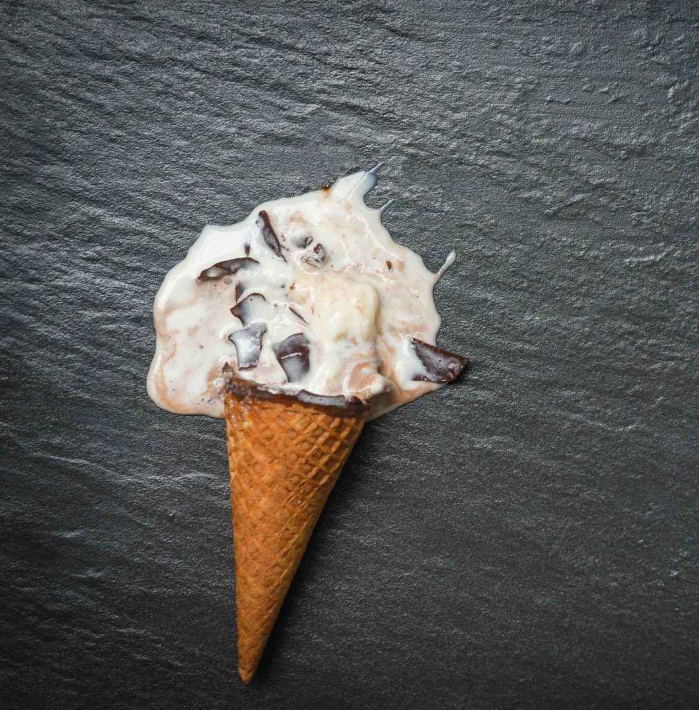 ice cream cone vanilla with chocolate dripping flowing on dark background